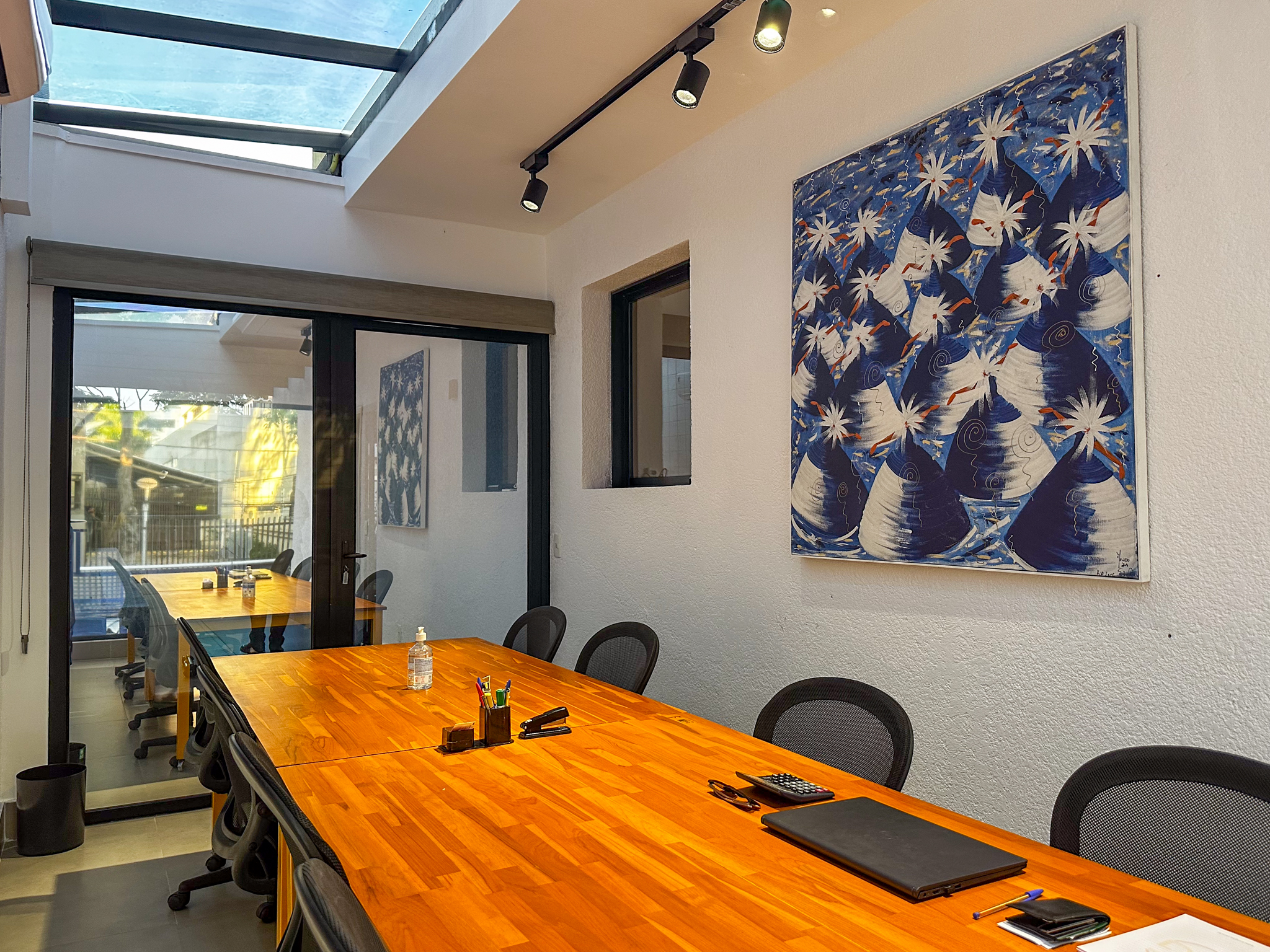 Sala de reunião do Espaço BIS com mesa longa, cadeiras ergonômicas e claraboia de vidro.